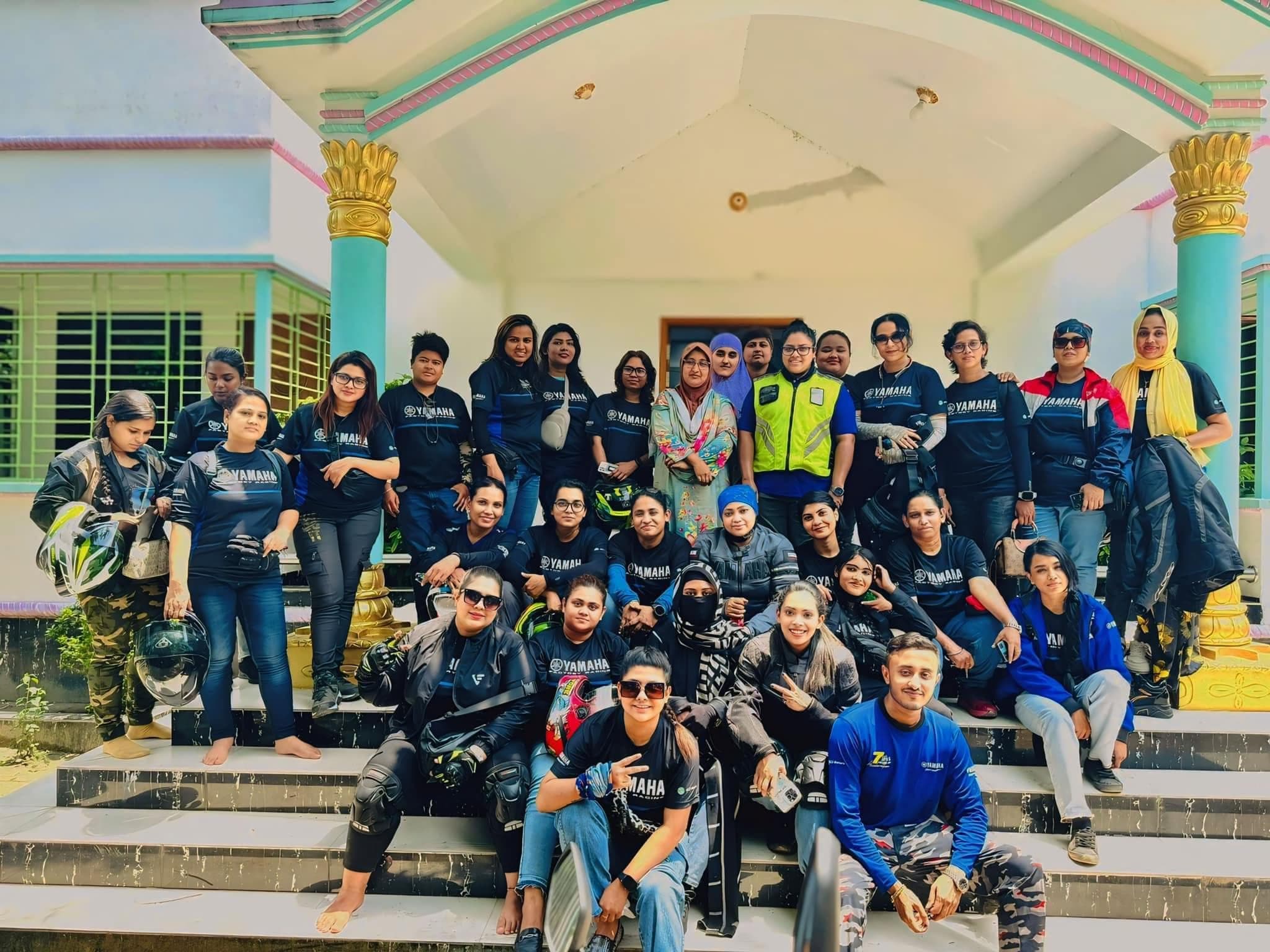 A biker group posed together on outdoor steps during a tour.