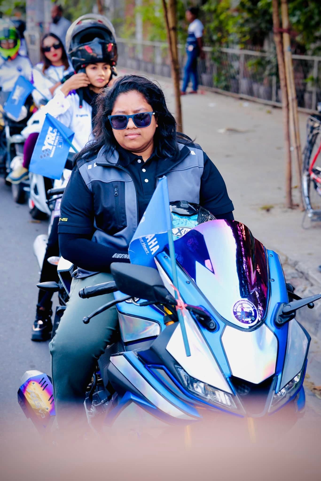 Portrait of Lina riding a blue Yamaha R15 at the front of a rally.