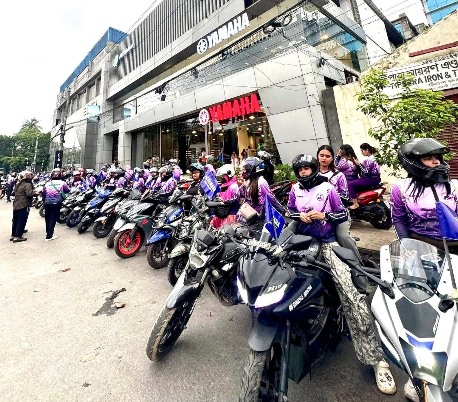 Women riders wearing purple jerseys outside the Yamaha showroom.