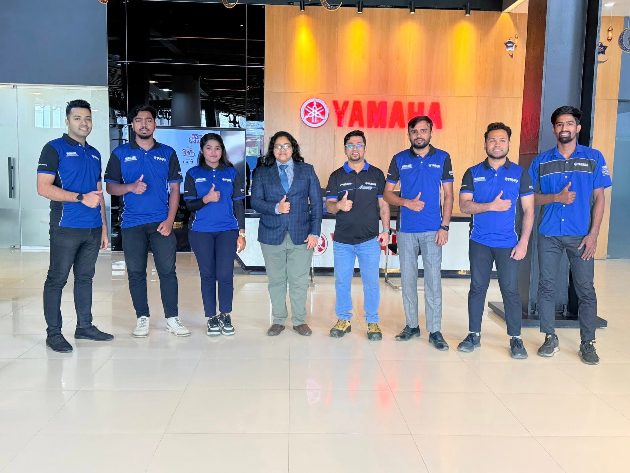 Lina standing with the Yamaha team indoors before a ride.