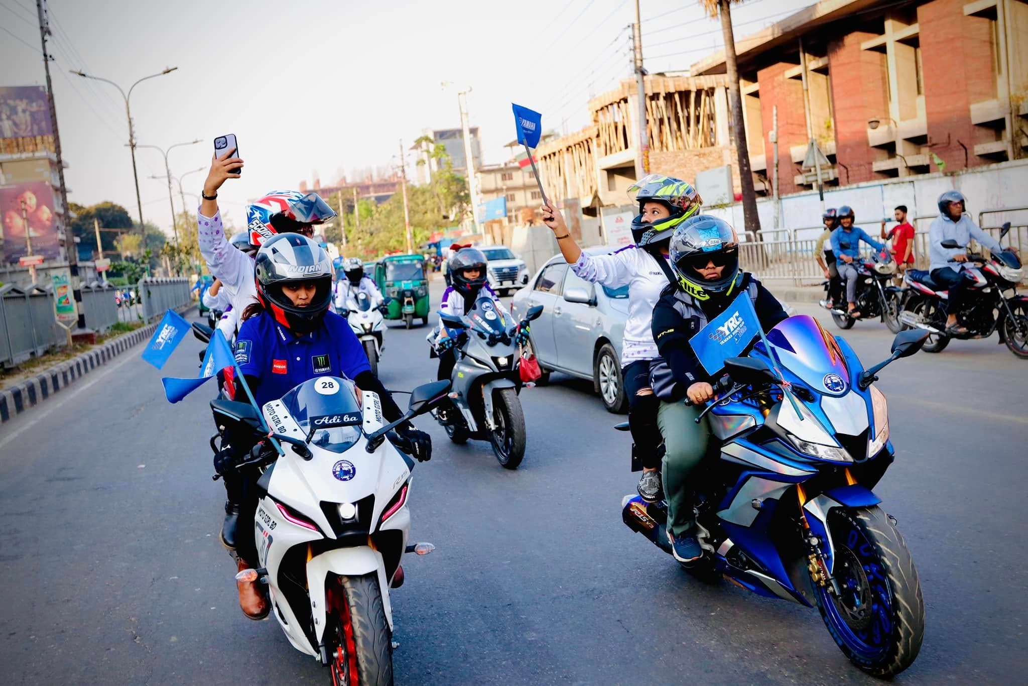 A Women's Day rally of riders moving along a city street.